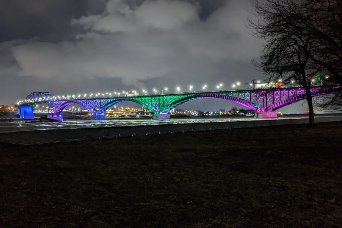Peace Bridge illuminated in green and purple for Rare Disease Day
